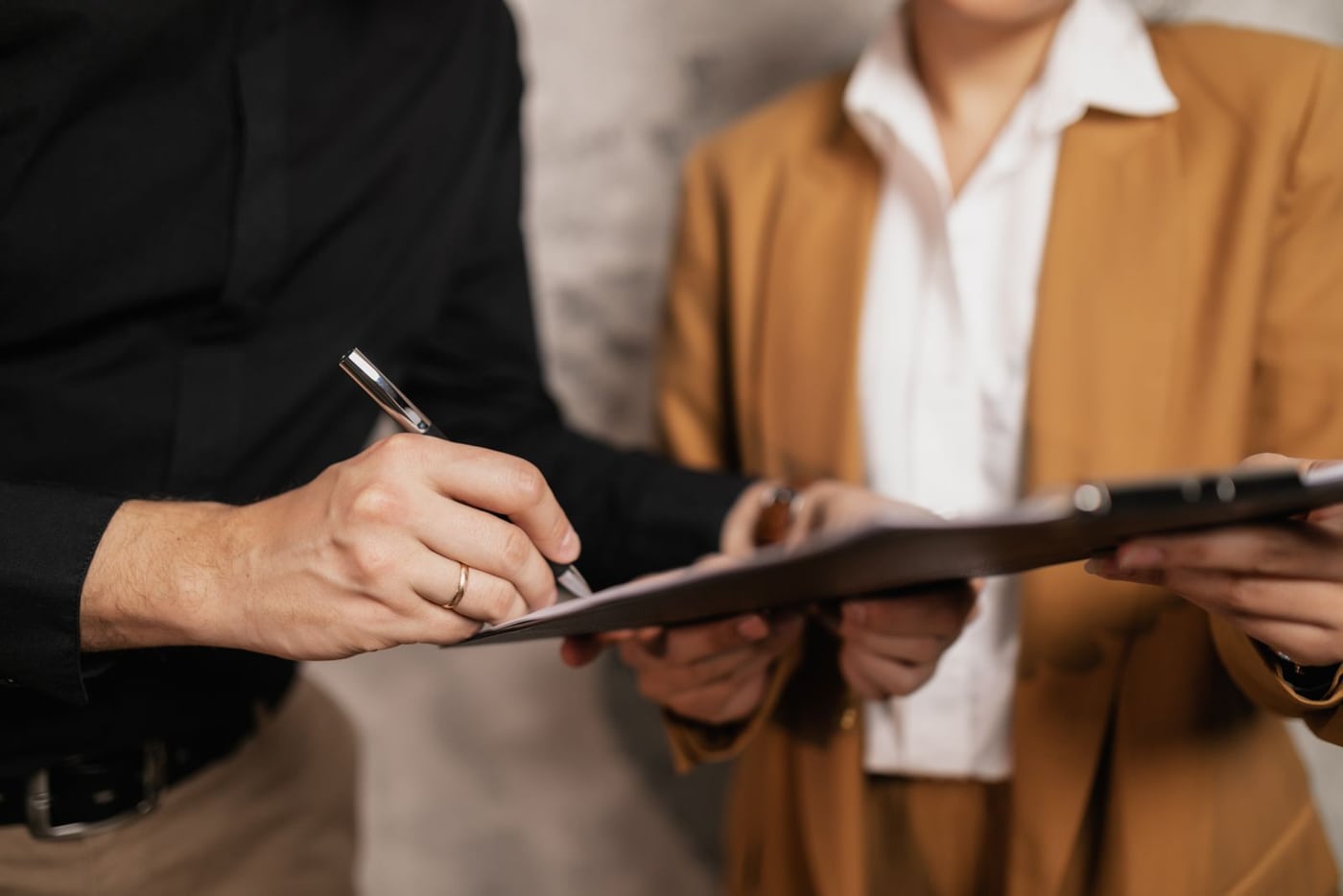 Two professionals completing a document on a clipboard