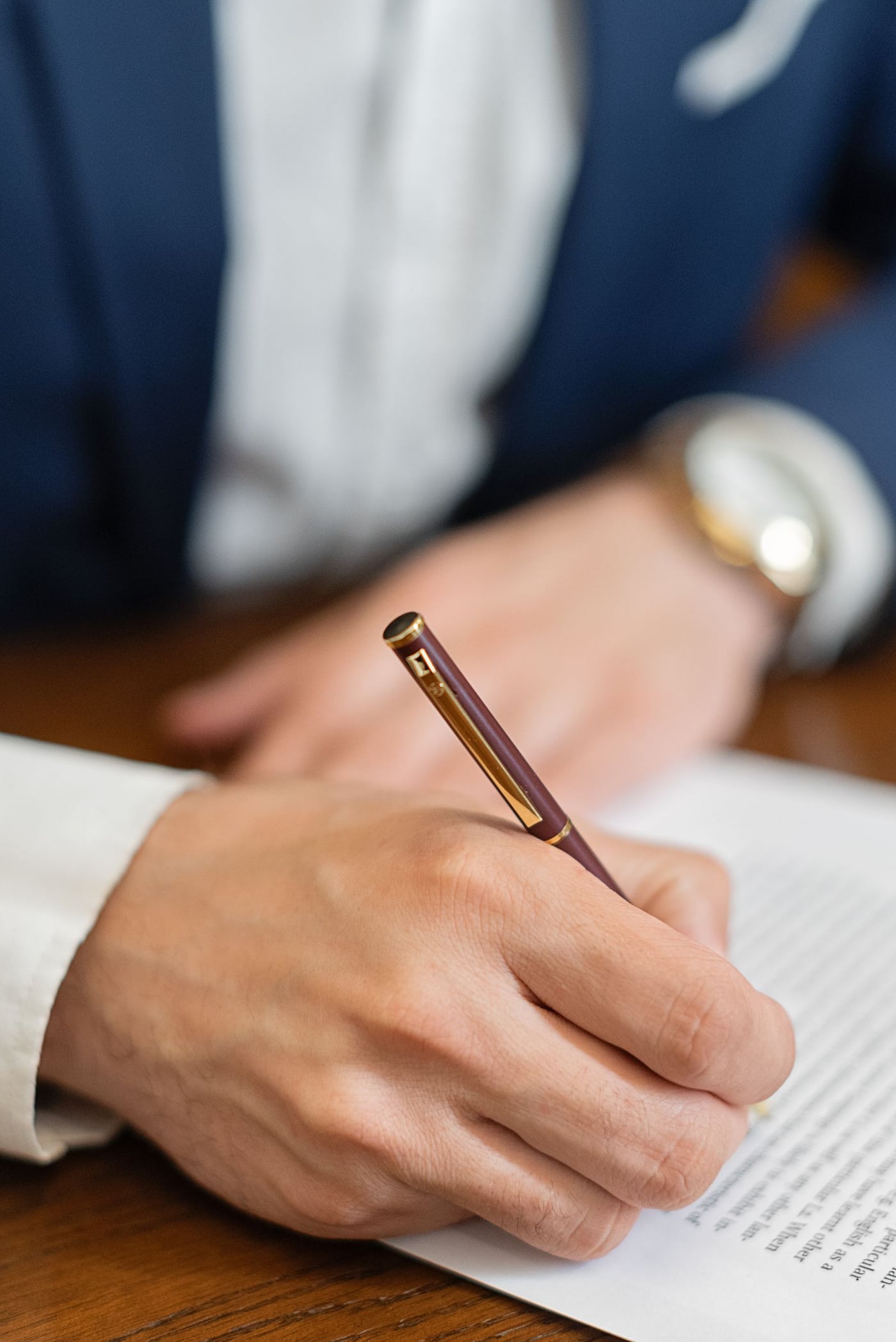A hand signing a document with a pen