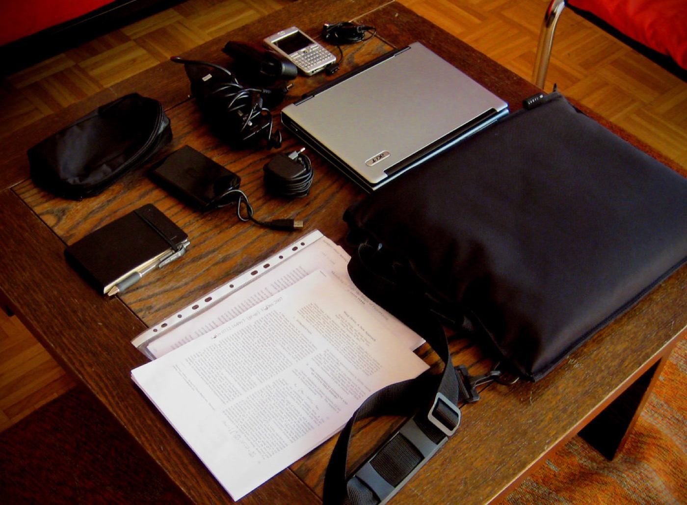 A desk with documents and a laptop bag