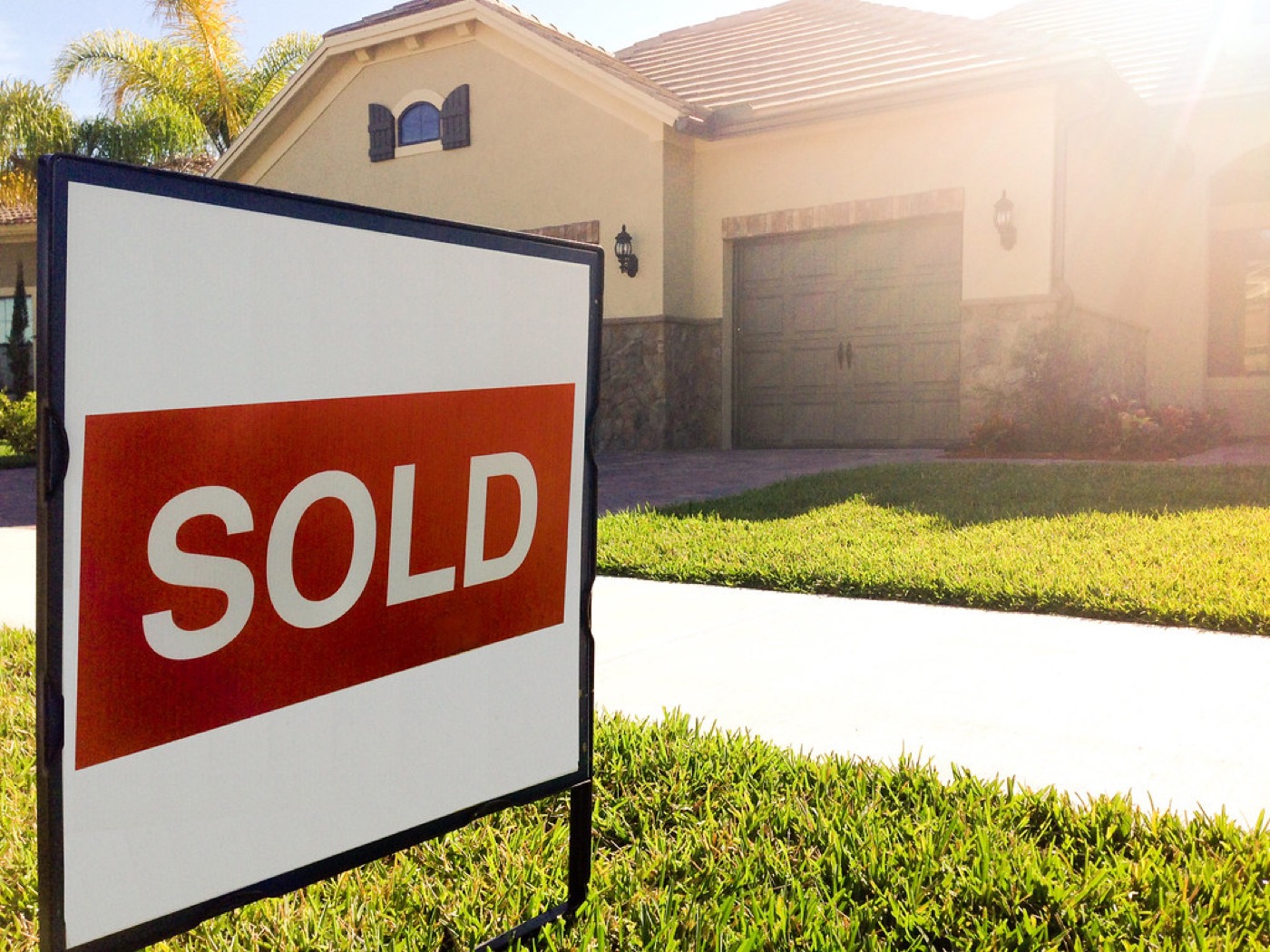A sold sign on the lawn outside a house