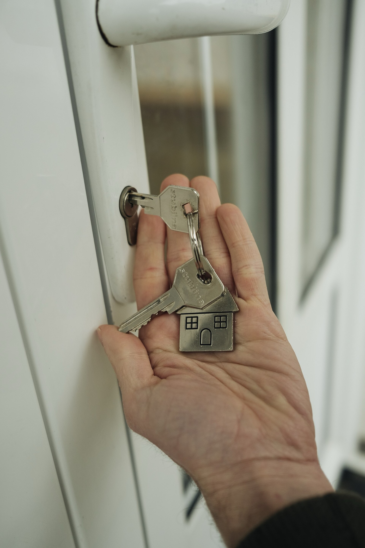 A hand holding house keys beside a front door lock