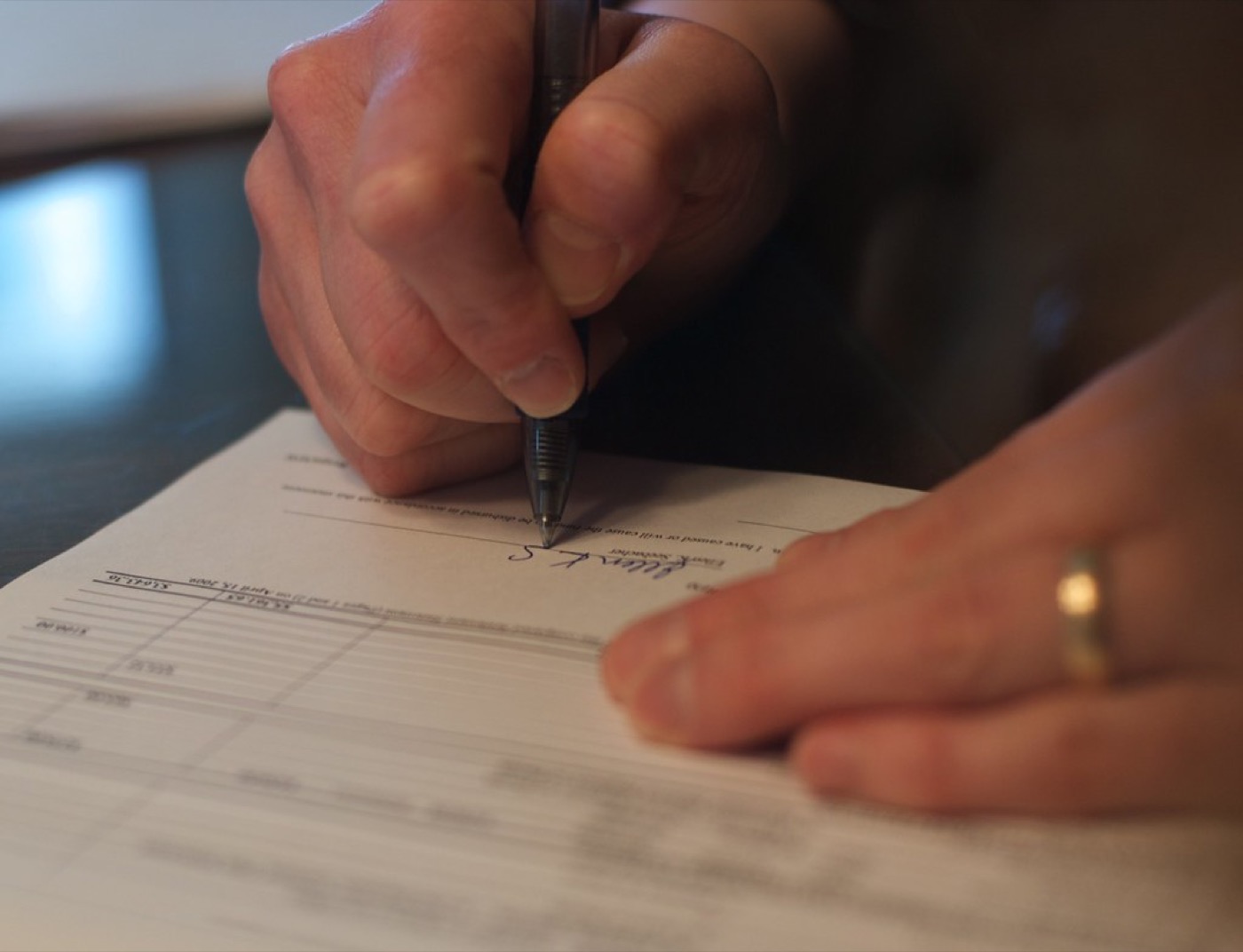 Hands signing mortgage documents at a table